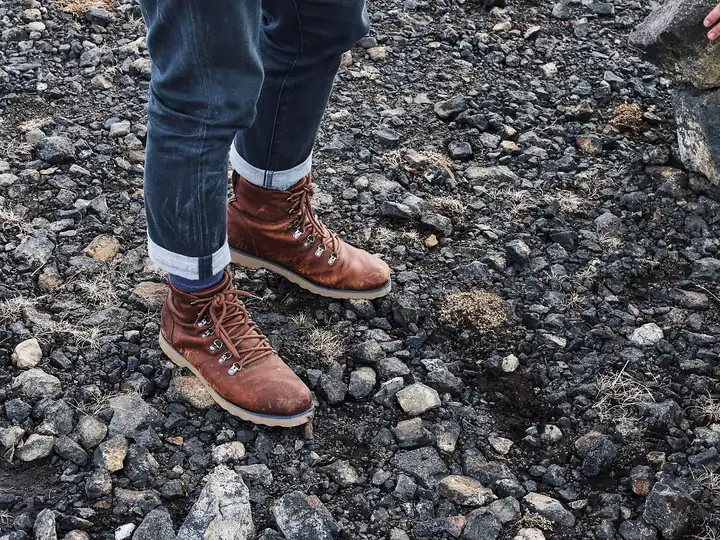 Brown leather hiking boots on dark gravel