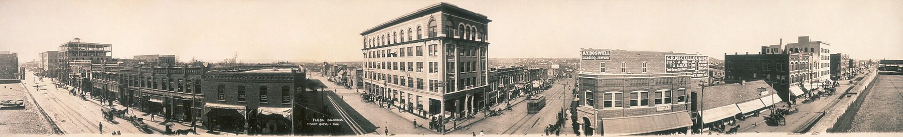 Sepia panorama of Tulsa in 1909: brick storefronts, awnings, a streetcar and horse-drawn wagons